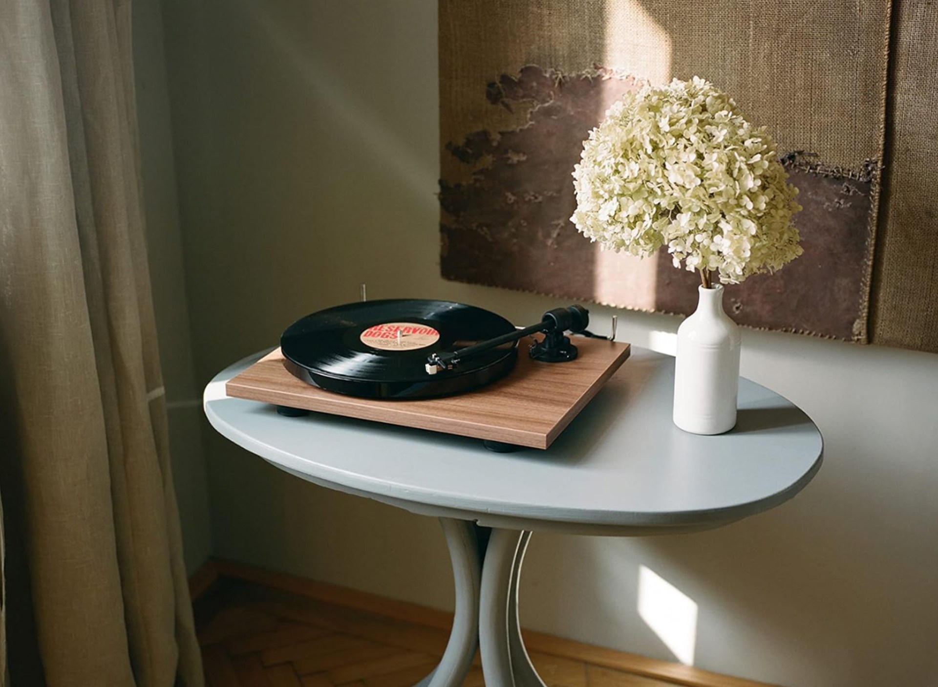 Pro-Ject E1 record player on a tiny grey table with flowers around in an apartment